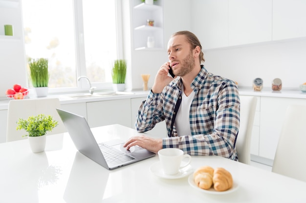 homem trabalha no laptop e fala no telefone