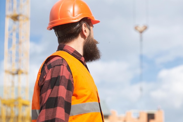 Homem trabalhador da construção civil em roupas de trabalho e um tema industrial de capacete de construção