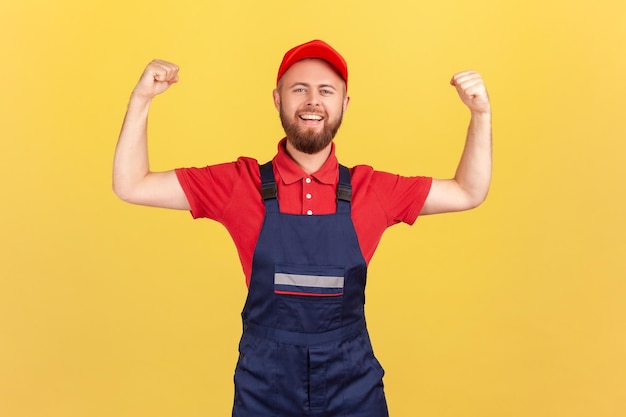 Homem trabalhador de pé com os braços levantados e mostrando seu poder olhando para a câmera com orgulho