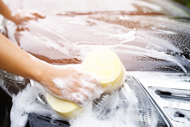 Homem trabalhador de pessoas segurando a mão esponja amarela e janela de limpador de espuma bolha para lavar o carro Conceito de lavagem de carro limpo Deixe espaço para escrever mensagens