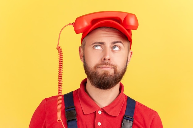 Homem trabalhador segurando o aparelho na cabeça e olhando cansado de ligar para o serviço de pedidos