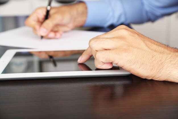 Homem trabalhando em tablet em fundo de madeira closeup