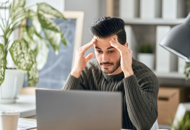 Homem trabalhando em um laptop em casa.