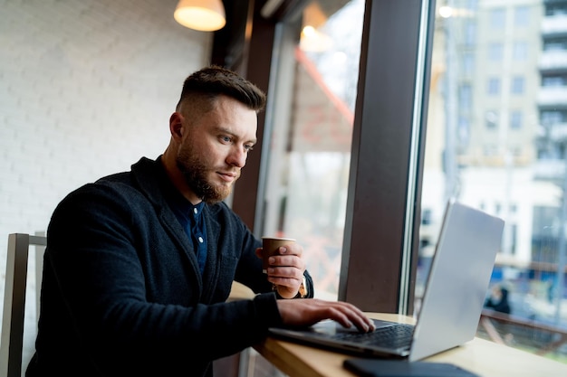 Homem trabalhando em um laptop em uma mesa Um homem sentado em uma mesa usando um laptop