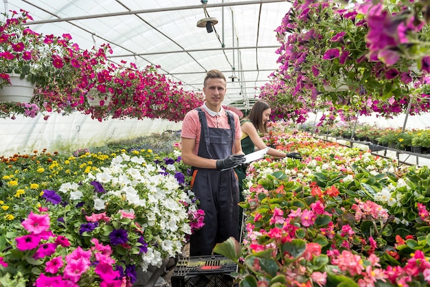 Homem trabalhando em um laranjal cheio de flores verifica as condições das plantas em uma estufa industrial