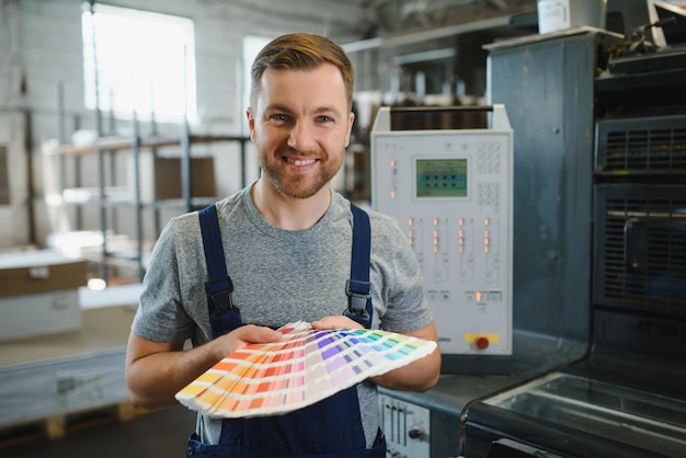 Foto homem trabalhando em uma gráfica com papel e tintas