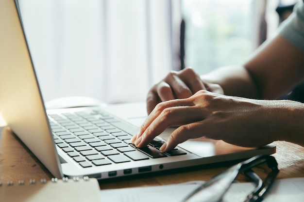 Homem, trabalhando, lar escritório, usando, um, computador laptop, ligado, tabela madeira