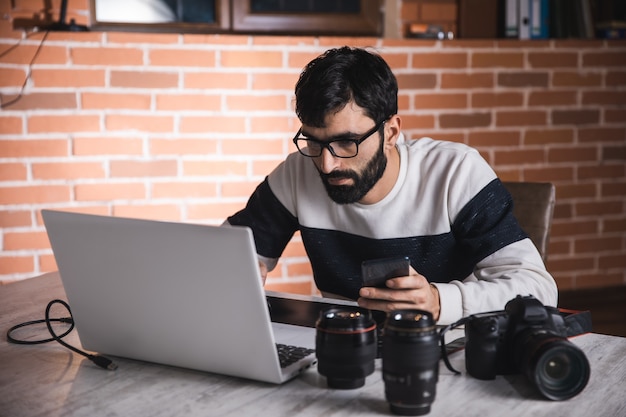 Foto homem trabalhando no computador com a lente na mesa