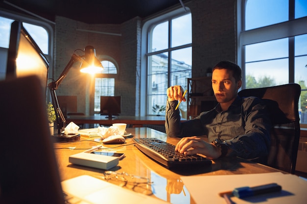 Homem trabalhando sozinho no escritório, ficando até tarde da noite.