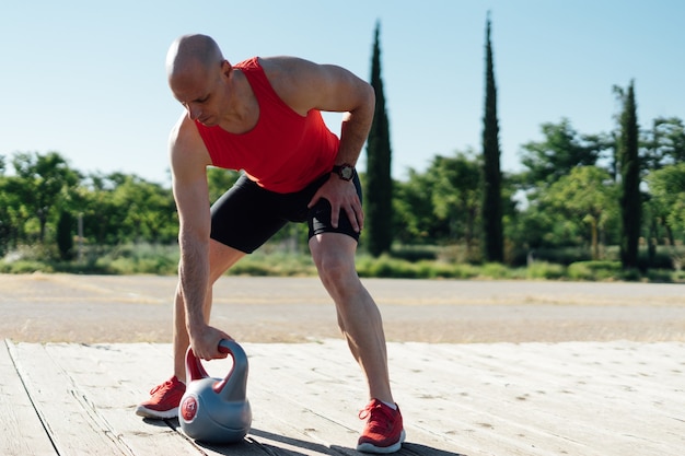 Homem treinando com kettlebell na cidade