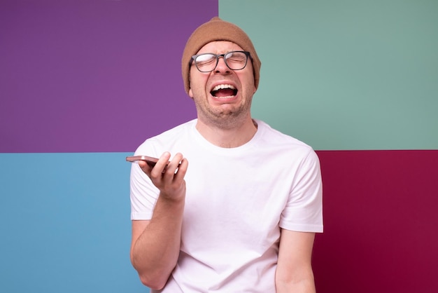 Homem triste caucasiano segurando seu telefone, ele está chorando porque perdeu o emprego Foto de estúdio