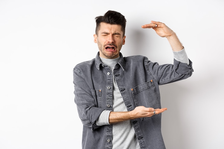 Foto homem triste chorando e mostrando um objeto de tamanho grande, moldando uma coisa grande e reclamando, soluçando em pé sobre um fundo branco.