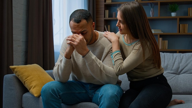 Homem triste desesperado sentado no sofá chateado com más notícias reclamando problema de vida carinhoso apoio da esposa