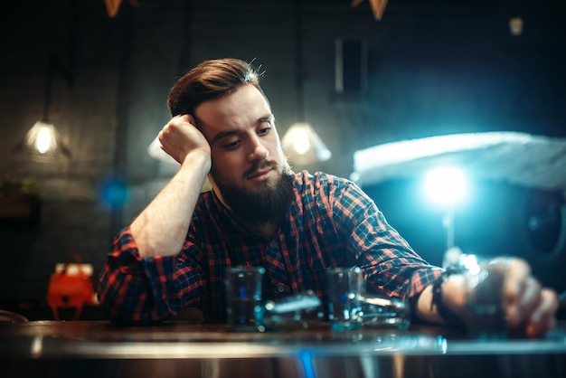 Homem triste sentado no balcão do bar, alcoolismo