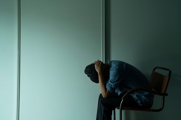 homem triste sentado no quarto escuro