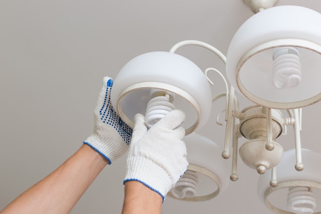 Homem troca uma lâmpada elétrica, eficiência energética.