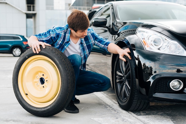 Homem, trocando, pneu carro, com, sobressalente
