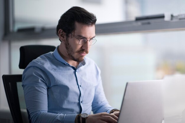 Homem turco de aparência autêntica concentrado focado em seu laptop e trabalhando com humor sério em um espaço de cópia de escritório moderno