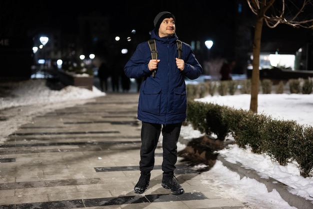 Homem turista com mochila na cidade à noite no inverno