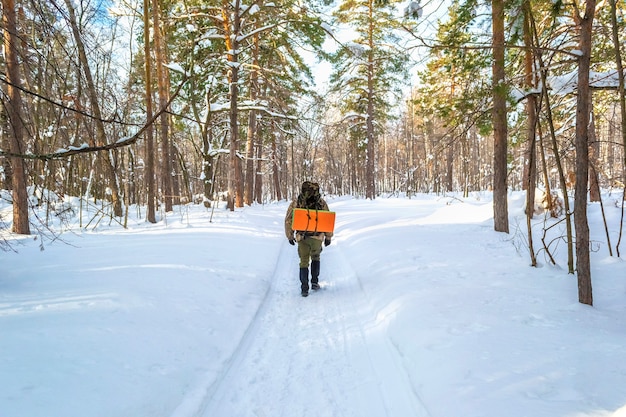 Homem turista com uma prateleira percorrendo o caminho de inverno na floresta