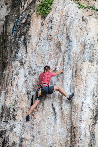 Homem turista escalando em uma parede de pedra calcária na província de Krabi, na Tailândia.