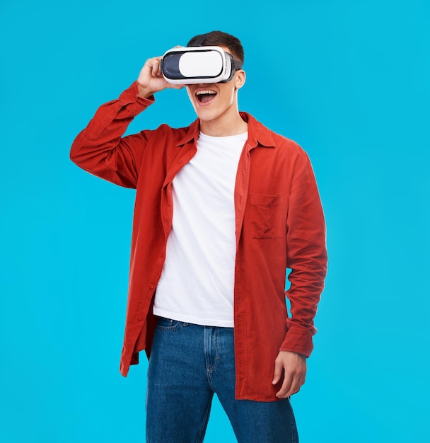 Homem uau e VR ou óculos futuristas para software de jogos mundo digital e visão de fantasia em um fundo azul Pessoa entusiasmada assistir em vídeo 3d tecnologia de realidade virtual e metaverso em estúdio