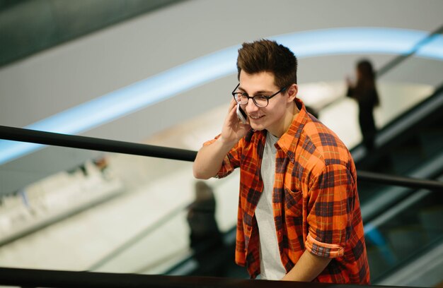 Homem usa smartphone na parede do shopping