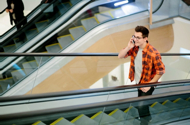 Homem usa smartphone na parede do shopping