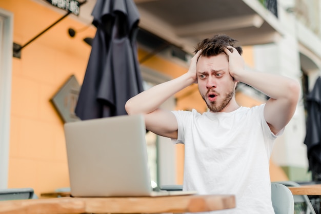 Homem, usando computador portátil, para, trabalho remoto, em, café