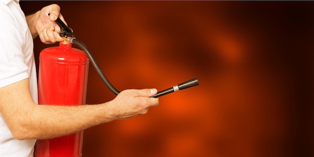 Homem usando extintor de incêndio contra um fundo cinza