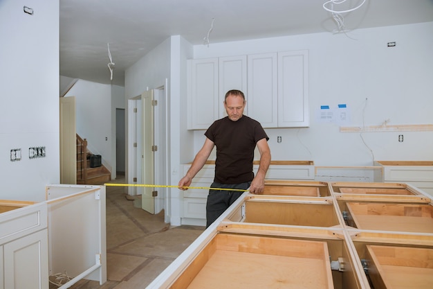 Homem usando fita métrica para medir na cozinha para a melhoria home.