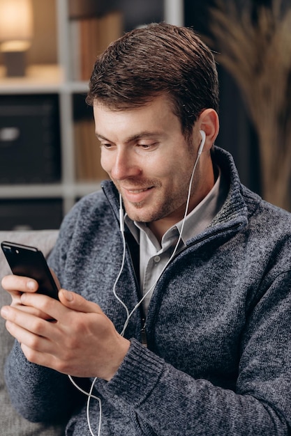 Homem usando fones de ouvido durante videoconferência em smartphone