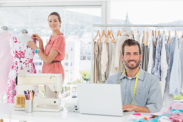 Homem usando laptop com designer de moda trabalhando no estúdio