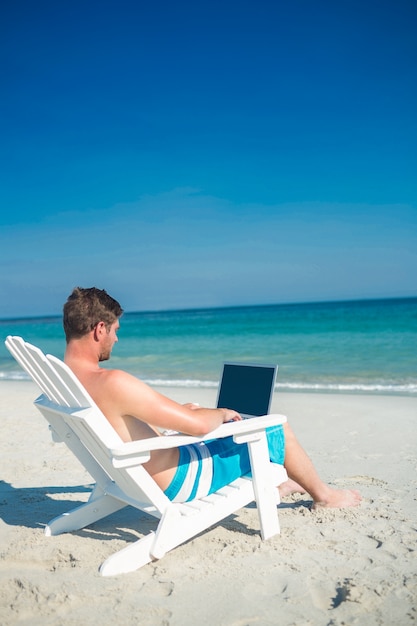 Homem, usando, laptop, deck, cadeira, praia