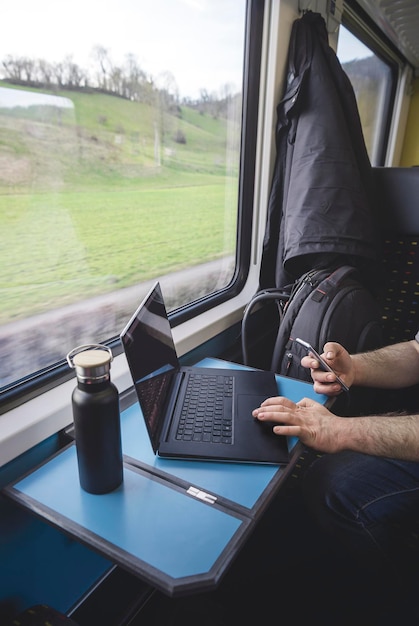 Homem usando laptop e telefone dentro do trem interior do trem suíço