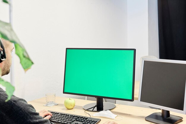 Homem usando laptop na mesa com uma tela verde