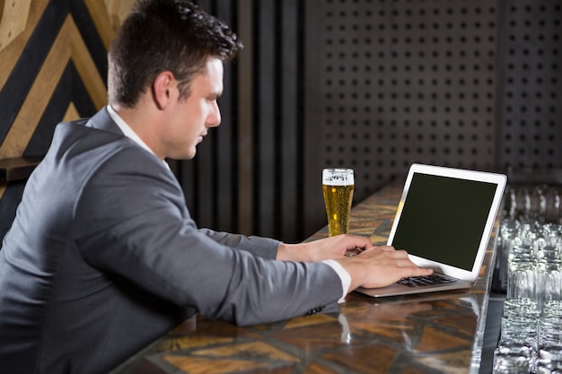 Homem usando laptop no balcão de bar