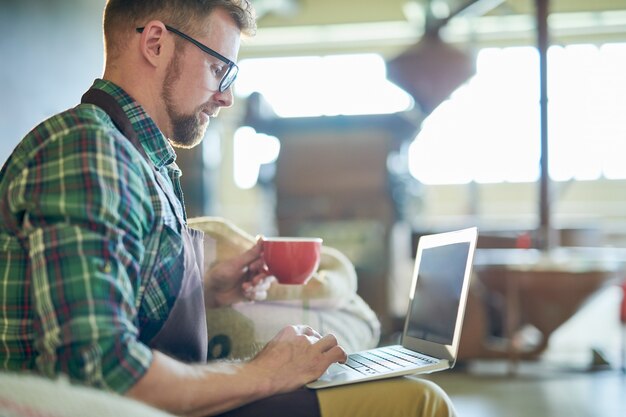 Homem usando laptop no café roastery