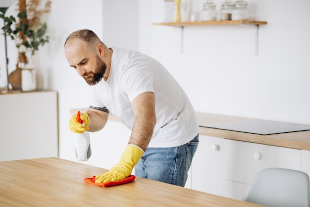 Homem usando luvas de borracha limpando na cozinha