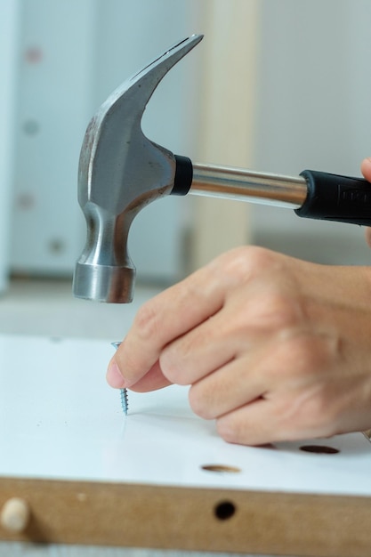 Homem usando martelo martelando um prego em tábuas de madeira montando ou reparando móveis em casa Renovação DIY reparação e desenvolvimento de conceitos de casa ou apartamento