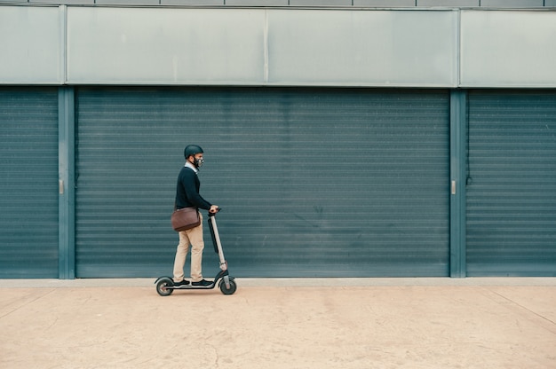 Homem usando máscara cirúrgica andando de scooter para trabalhar