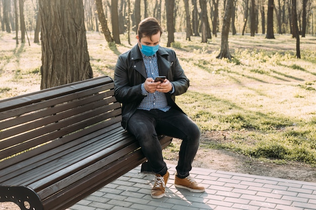 Homem usando máscara usando smartphone, conceito de cuidados de saúde. quarentena do coronavírus.