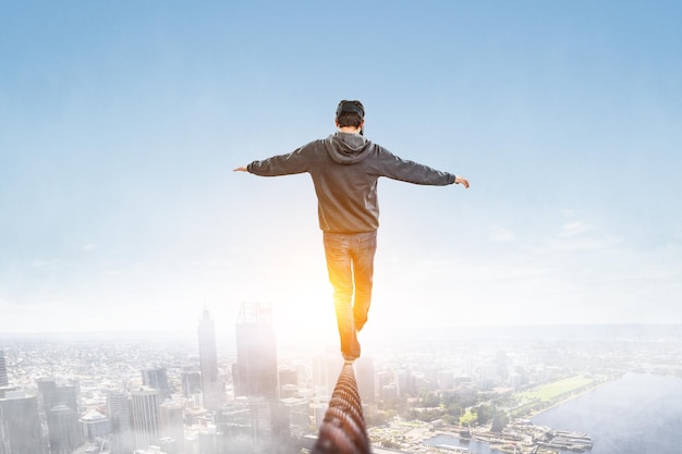 Homem usando óculos de realidade virtual e equilibrando na corda. Mídia mista