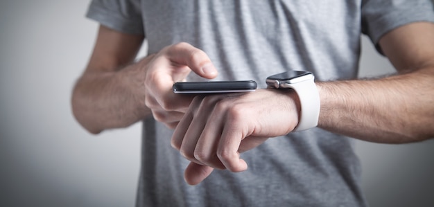 Homem usando relógio inteligente e smartphone. Estilo de vida. Tecnologia