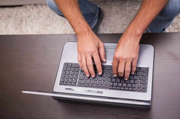 Homem usando seu laptop na mesa de café