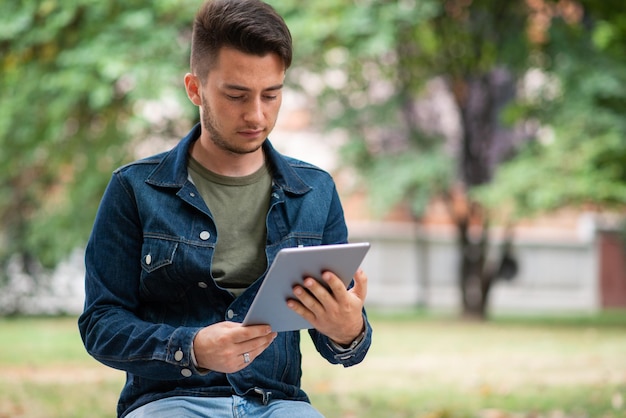 Homem usando seu tablet enquanto está sentado em um banco no parque