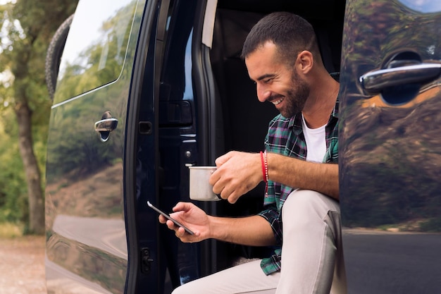 Homem usando seu telefone sentado na porta de sua van