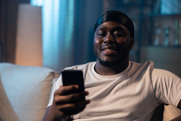 Homem usando smartphone à noite navegando na internet e atualizando a mídia social jovem com barba