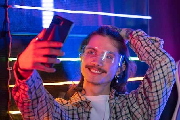 Homem usando smartphone e tirar selfie na boate com luz neon