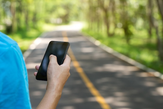 Homem usando smartphone em uma estrada no parque